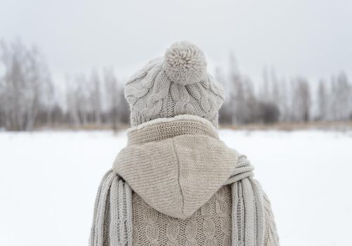 Lonely woman stands back in a field in winter