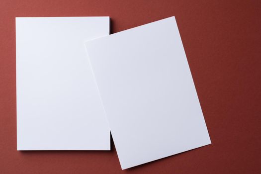Blank white business cards on burgundy paper background, top view