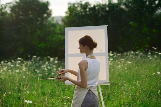 woman artist outdoors with palette of paints paints a picture. High quality photo