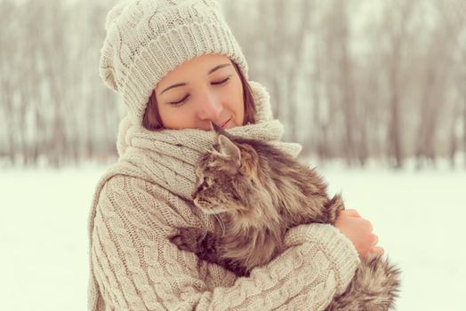 Young happy woman holds fluffy cat in winter