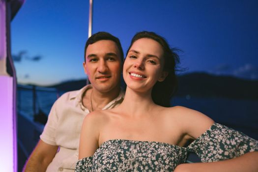 Portrait of happy loving couple on the yacht in the evening