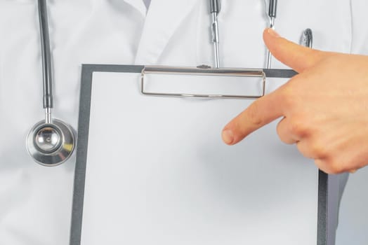 Unrecognizable man doctor is pointing on blank clipboard, space for text