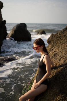 woman in swimsuit sunglasses ocean rocks posing. High quality photo