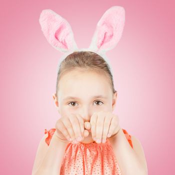 Beautiful little girl dressed in Easter bunny ears on a pink background