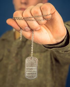 Military man shows steel badge, close-up, space for text