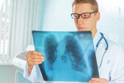 Male physician looks at x-ray picture of lungs in a clinic