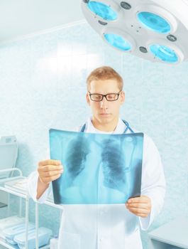 Man physician examines x-ray picture of lungs in a hospital