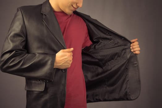 Young man opens his black jacket, space for text