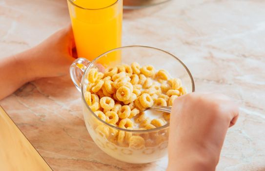 Child has breakfast of cereal flakes, face is not visible