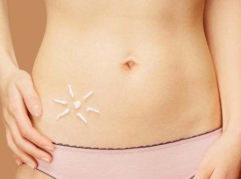 Cream in the form of sun on the skin of the belly, concept of skincare