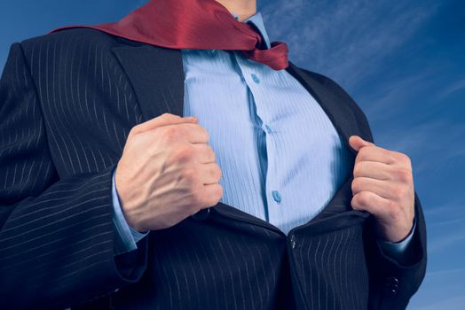 Businessman opens suit showing his shirt on background of sky, face is not visible