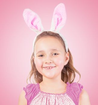 Portrait of little happy girl in Easter bunny ears on a pink background
