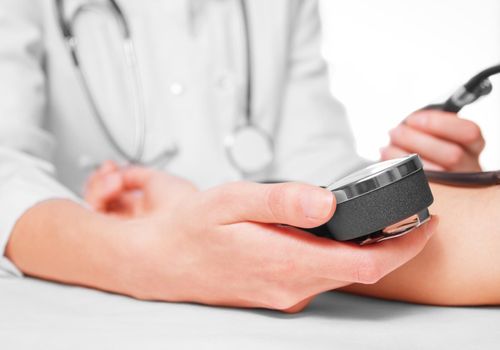 Unrecognizable doctor measures blood pressure a patient, side view