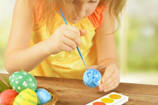 Little girl is painting egg for happy Easter holiday