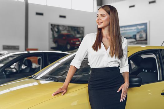 Young woman checking out a new car she is going to buy in car salon