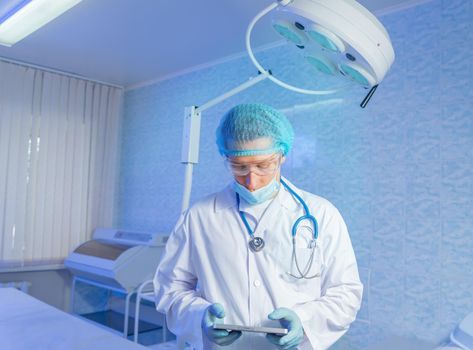 Man doctor surgeon works on a tablet computer in hospital