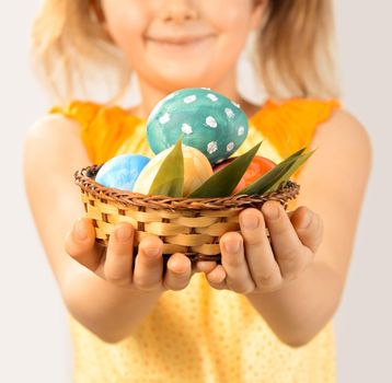 Girl gives Easter basket with colored eggs, focus on eggs