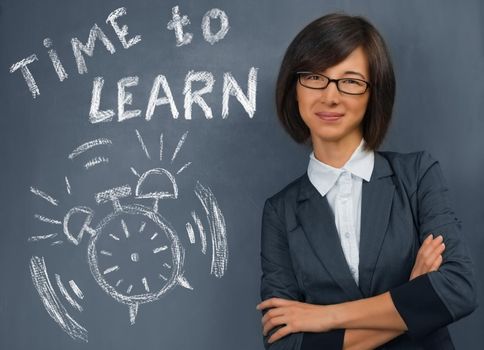 Young woman stands near blackboard with text time to learn