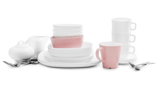White and pink plates, sugar bowl and mugs isolated on white background. Ceramic tableware.