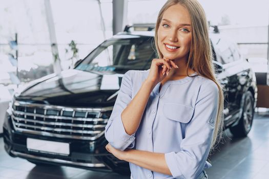 Young woman checking out a new car she is going to buy in car salon