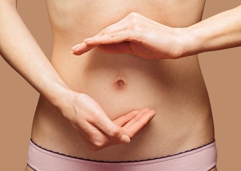 Unrecognizable woman holds her hands in circle shape in front of her abdomen