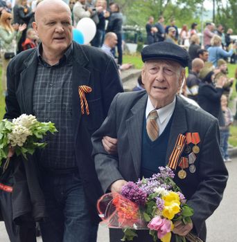PYATIGORSK, RUSSIA - MAY 09, 2017: The son supports the elderly father on a Victory Day