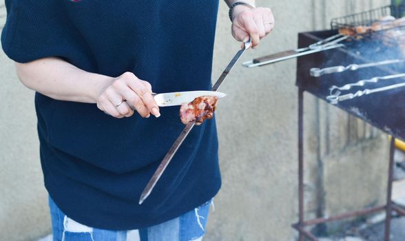 Women's hands cut barbecue meat Skewer on grill