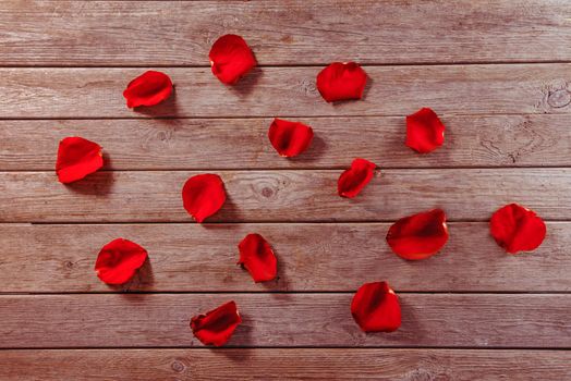 Many red rose petals on a wooden table