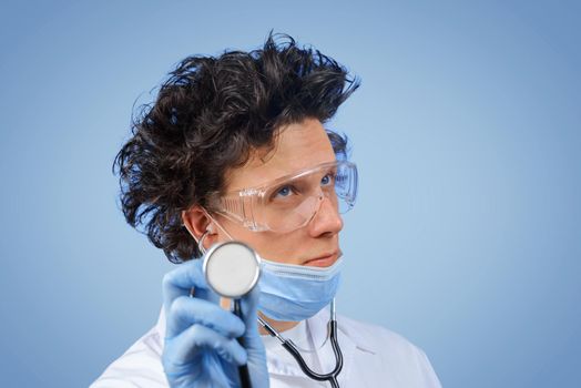 Bizarre doctor listens with stethoscope something in the air, space for text