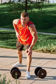 sporty man in the morning in the park with dumbbells exercise. High quality photo