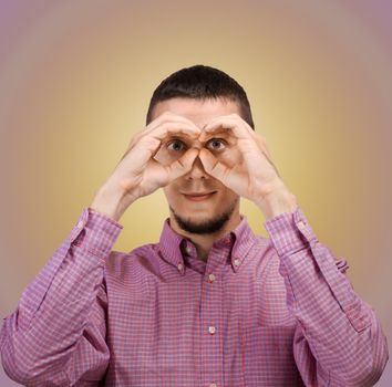 Young man searching for solutions making binoculars with his hands