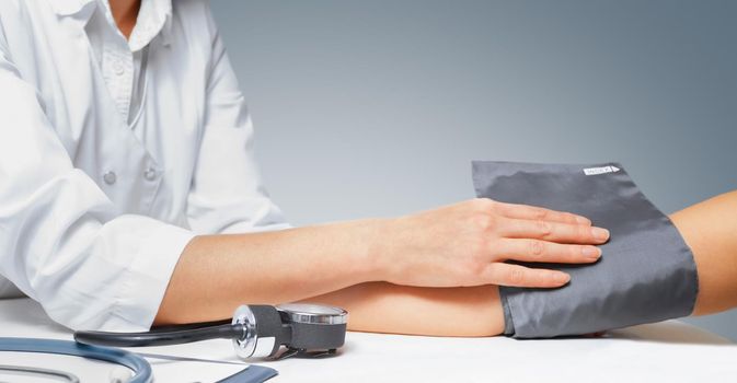 Doctor puts cuff of sphygmomanometer on the patient's arm
