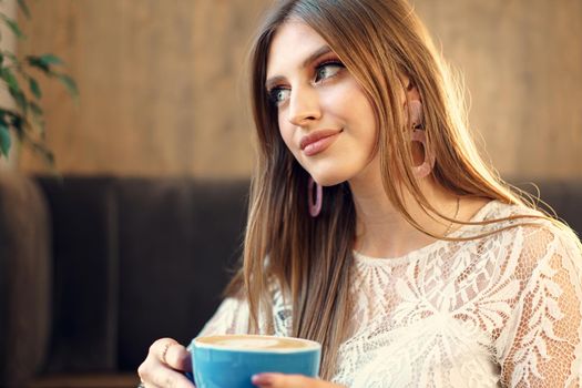 Nice young woman enjoying cup of coffee in a coffee shop. Close up.