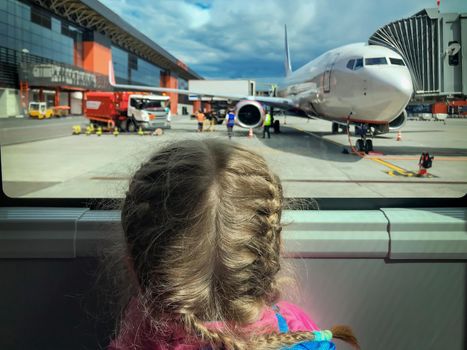 Image of a girl at airport looking at airplane