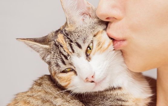 Happy woman kisses orange tabby cat