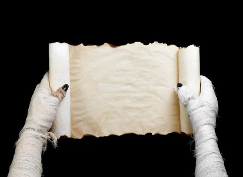 Mummy in one hand keeps vertical manuscript on black background. Space for text.