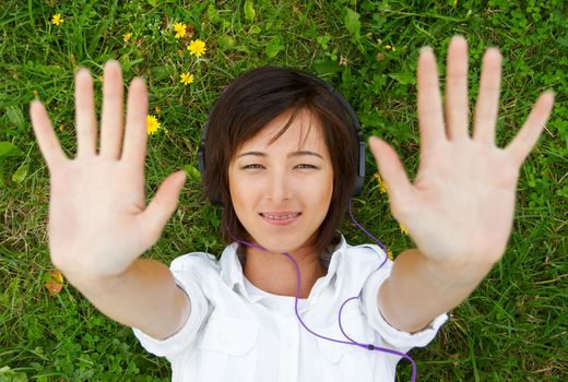 Smiling young woman listens to music on meadow