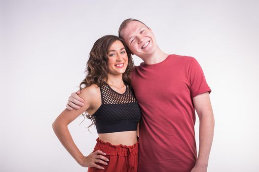 Portrait of young healthy sporty couple hugging on white background