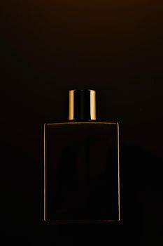 Men's fragrance of perfume or eau de toilette. Promotional photo of a black bottle on a dark background. Layout for copying text.