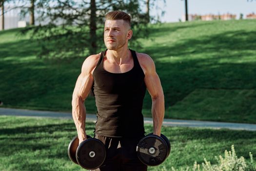 pumped up sports Vykhino in the park with dumbbell workout. High quality photo