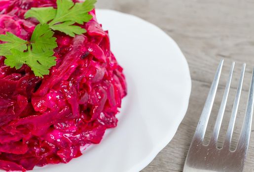 Beet salad with parsley on white plate, close-up