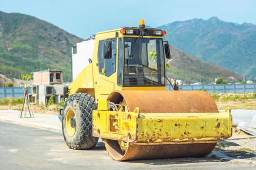 Large view on the big yellow road rollers working on the new modern multi-storey buildings district road construction site under blue sky. Civil building industry.