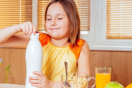 Little girl opens bottle of milk for cereal flakes