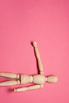 wooden mannequin on pink background posing close-up. High quality photo