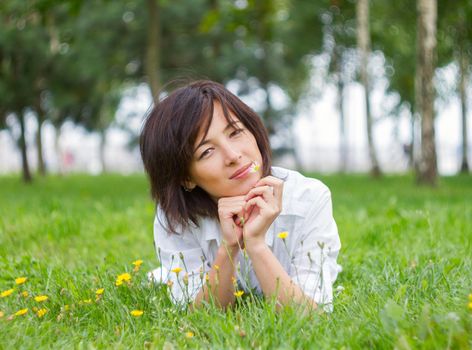 Beautiful young woman smiling with daisy in natural environment