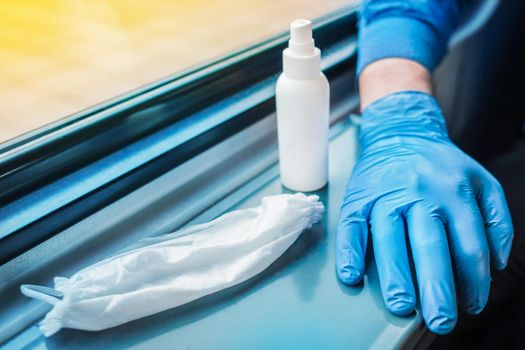 A person's hand in a protective medical glove lies next to a used medical mask and antiseptic. Hygiene and safety concept against coronavirus.