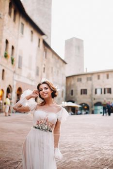 A bride in a white dress in the old town of San Gimignano.A girl walks around the city in Italy.Tuscany