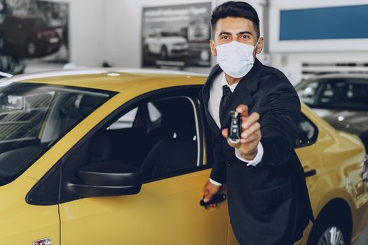 Man car dealer wearing protective medical mask on his working place, coronavirus prevention concept
