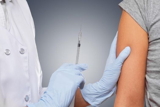 Physician makes vaccination in the shoulder of patient