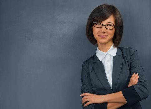 Young woman in a suit standing near the blackboard, space for text